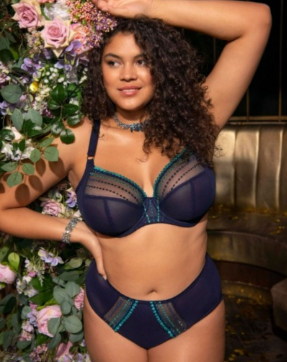 Volslank model met krullend haar in een lingerie set van Elomi Matilda in blauw met turqoise