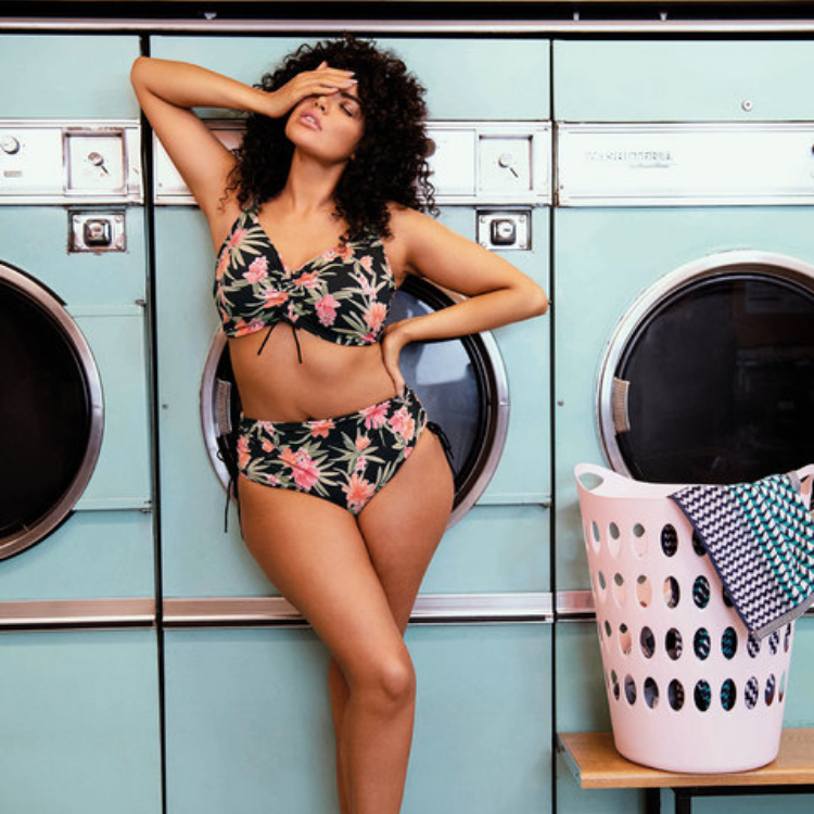 vrouw met hand op gezicht voor wasmachines in bikini